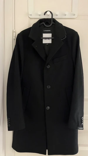 Svart kappa från J.Lindeberg - Pris kan diskuteras! Stilren svart kappa från J.Lindeberg i mycket bra skick. En tidlös och elegant modell som passar lika bra till vardag som till mer uppklädda tillfällen. Kappan är köpt för 5 500 kr och har endast använts 2–3 gånger. Klassisk design med knäppning framtill, snygg krage och välsydd passform. Hör gärna av dig vid frågor eller om du vill ha fler bilder!