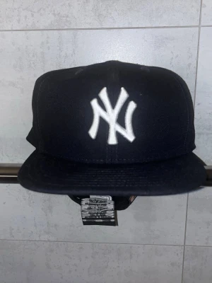 Yankees keps New Era 2010 Edition - Bilderna visar en svart New York Yankees keps från New Era, inte en väst. Kepsen har broderad logga fram och MLB-logga bak.