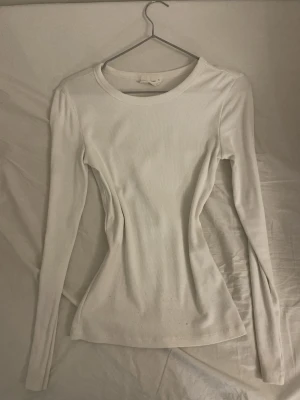 Vit ribbad långärmad topp XS från Gina Tricot  - Säljer en enkel och stilren vit långärmad topp från Gina Tricot i storlek XS. Toppen är ribbad och har en rund halsringning. Materialet är mjukt och stretchigt, perfekt för layering eller att bära som den är. Passformen är slim och den är helvit utan mönster. Från Gina Tricot i storlek xs men passar även dom som bär s