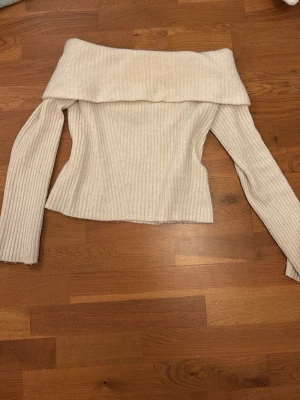 Offshoulder ribbad tröja från H&M - Säljer en ljusbeige offshoulder tröja från H&M i storlek S. Tröjan är ribbstickad med lång ärm och har en bred, nedvikt krage som ger en snygg och trendig look. Perfekt för dig som gillar stilrena och bekväma plagg med lite edge.