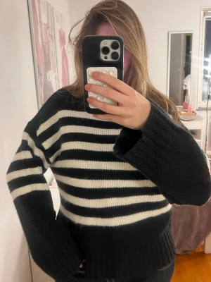 Randig svartvit stickad polotröja från NAKD - Säljer en mysig stickad polotröja med breda svarta och vita ränder. Tröjan har en hög krage som kan vikas ner, långa ärmar med bred mudd och en loose fit. 