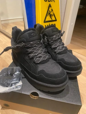 Svarta UGG lowmel - Säljer ett par svart UGG lowmel som är perfekta för vintervädret. Skorna har aldrig används och bara testats inomhus. Skorna kommer med original snörning och ett extra par med skosnören i hel svart färg samt är skorna gjorda av ett mocka material. Pris kan diskuteras!