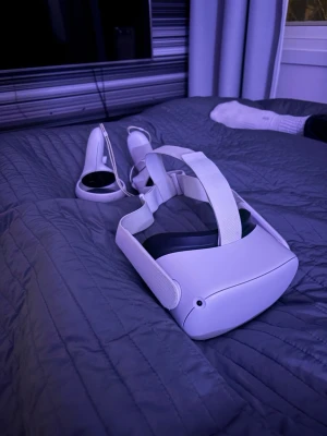 Meta Quest 2 VR-headset - Meta Quest 2 VR-headset med två handkontroller. Perfekt för spel och upplevelser i virtuell verklighet. Bekväm huvudrem och intuitiva kontroller ingår.