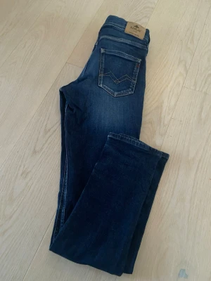 Mörkblå Replay jeansbyxor Wallys - Säljer ett par mörkblå jeans från Replay med klassisk femficksdesign och snygga kontrastsömmar på bakfickan. Jeansen har en rak passform och är tillverkade i slitstarkt denimtyg. Modell: Wallys