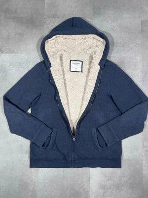 vintage Abercrombie & Fitch fodrad zip-up hoodie - Säljer en vintage Abercrombie & Fitch fodrad zip-up hoodie i snygg mörkblå färg. 🧵 Märke: Abercrombie & Fitch 👕 Storlek: Medium 🎨 Färg: Mörkblå / navy 📌 Design: Fodrad zip-up hoodie 📍 Skick: Mycket bra, se bilder!  Beskrivning: • Tidlös vintage-design från Abercrombie & Fitch • Fodrad zip-up hoodie – varm och bekväm • Praktisk huva och dragkedja • Inga fläckar, noppor eller skador (kontrollera bilder) • Lätt att matcha med jeans, chinos eller mjukisbyxor