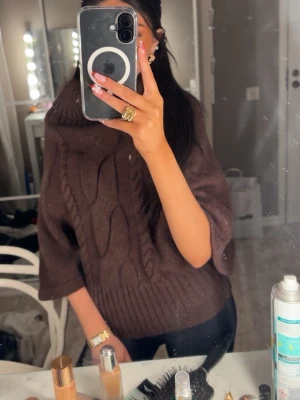 Brun polotröja med korta ärmar - Säljer en brun polotröja med bred ribbad krage och korta ärmar. Tröjan har ett snyggt kabelstickat mönster framtill och breda ribbade muddar vid hals och nederkant. (intressekoll)