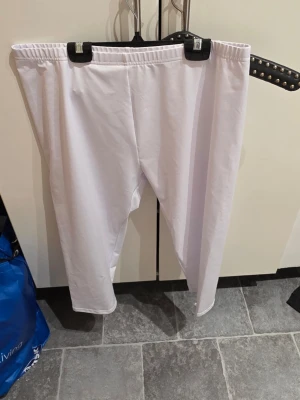 Vita leggings i polyester/spandex 2XL - Säljer ett par vita leggings i storlek 2XL med elastisk midja. Materialet är mjukt och stretchigt, tillverkat av 90% polyester och 10% spandex. Perfekta för dig som gillar bekväma och flexibla byxor med enkel design.