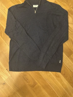 Mörkblå stickad half zip från Lindbergh - Snygg mörkblå stickad tröja från Lindbergh i slim fit med half zip-dragkedja vid halsen. Tröjan har långärmad design och ribbade muddar vid ärmslut och nederkant. Perfekt för dig som gillar stilrena och klassiska plagg.