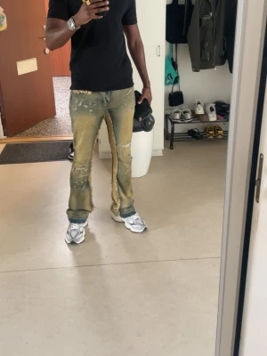 Distressed ljusbruna jeans med slitningar - Säljer ett par ljusbruna jeans med tydliga slitningar och råa kanter längs benen. Byxorna har en baggy passform och är tillverkade i jeansmaterial. De har en cool, sliten look som passar dig som gillar streetstyle och vill sticka ut. Är 184 cm