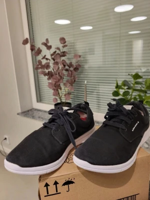 Svarta sneakers från Björn Borg 41 - Säljer ett par svarta sneakers från Björn Borg med vit sula och vita detaljer på hälen. Skorna har snörning och är tillverkade i textilmaterial med en rund tå och platt sula. Perfekta för dig som gillar stilrena och bekväma skor.