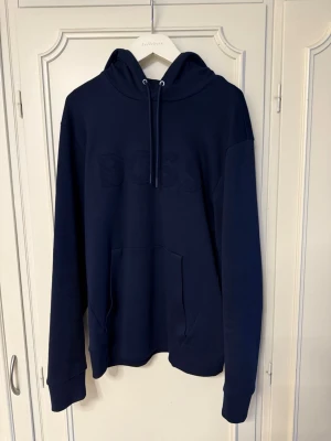 Mörkblå BOSS hoodie - Säljer en mycket fin mörkblå hoodie från BOSS i storlek M. Hoodien är i nyskick, använt fåtal gånger!
