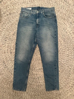 Blå jeans från Zara, rak modell - Snygga blå jeans från Zara i loose modell med fem fickor och normal passform. Jeansen har en ljus tvätt med subtila slitningar och är tillverkade i bomull. Perfekta för en avslappnad och trendig look.