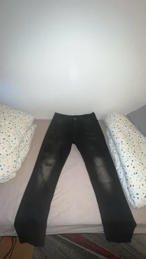 Svarta jeans kings Will dream storlek 32 - Svarta jeans med skinny fit och coola slitningar framtill. Jeansen har en något tvättad look och detaljer med små färgstänk och slitna partier både fram och bak. Klassisk femficksmodell och knappgylf. Perfekta för en edgy streetstil.