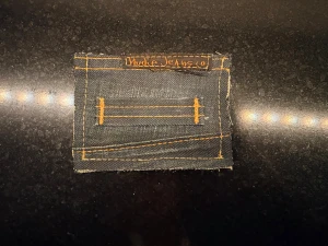 plånbok Nudie Jeans - Unik liten plånbok gjord av mörkblå denim med orange kontrastsömmar och Nudie Jeans-märke. Rektangulär form med ficka och detaljerad sömnad, perfekt för kort eller småsaker. Materialet är klassisk jeansväv i bomull.