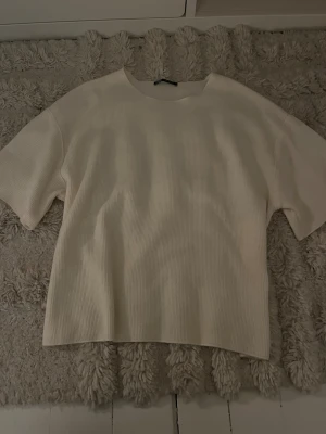 Vit ribbad topp med kort ärm - En superfin enkel tröja med korta ärmar. Materialet är lite ribbat och väldigt skönt. Har använt den max två gånger så den är i väldigt bra skick! 