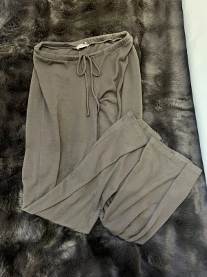 Bruna byxor från Nelly  - Bruna/gråa byxor från Nelly i storlek S byxorna är i helt okej skick men har ett hål vid rumpan men man skulle kunna sy ihop de förutom de är dom i rätt så bra skick 