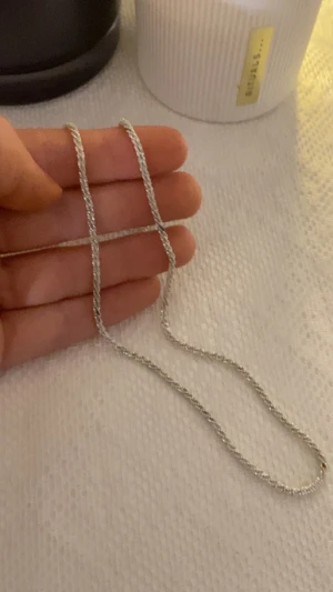 Tunn silverfärgad kedja - Snygg tunn halskedja i silverfärgat metall med tvinnad design. Kedjan har en enkel karbinlås och passar perfekt till lager-på-lager eller som ett diskret smycke. Längden är klassisk och kedjan ligger snyggt mot huden.