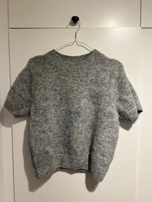 Grå stickad tröja från Gina Tricot - Mysig grå stickad tröja från Gina Tricot med korta ärmar och rund hals. Storlek L. Perfekt skick har bara använt den 2 gånger 🩷