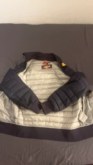 Parajumper mörkblå dunjacka - Snygg mörkblå dunjacka från Parajumpers med quiltad design och ribbade muddar. Jackan har dragkedja framtill, två fickor med dragkedja och klassisk patch på ärmen. Perfekt för kyliga dagar och har en sportig look. Inte så använd riktigt fin storlek S