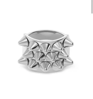 Silvrig ring med spikes - Cool och edgy ring i blankt silvrigt metallmaterial med flera utstickande spikes runt hela bandet. Perfekt för dig som gillar att sticka ut och vill ha en unik accessoar med attityd. Ringen har en bred form och ger en riktigt tuff vibe.