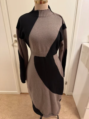 Stickad klänning från SHEIN i svart och beige - Snygg stickad klänning från SHEIN i svart och beige med coolt grafiskt mönster. Modellen är figurnära med lång ärm, ribbad hög krage och markerad midja. Perfekt för dig som gillar en trendig och bekväm look under kyligare dagar.