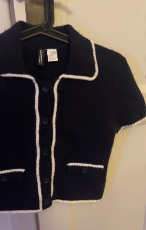 Marinblå kort kofta från Ginatricot - Kort marinblå kofta från h&m med vita detaljer.