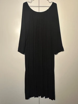 H&M svart klänning, storlek S - Svart klänning med lång ärm och en avslappnad passform. Klänningen har en rund halsringning fram. Den har en lös silhuett och en volang nedtill.