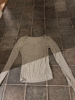 Ljusgrå långärmad topp - En enkel och stilren ljusgrå långärmad topp med rundad hals. Tunn och mjuk i materialet, perfekt för lager-på-lager eller att bära som den är. Passformen är normal och tyget känns lätt mot huden. Lappen med storleken klippte ja bort då den skavde 