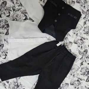 Baby kostym - Klassisk vit skjorta med lång ärm och knappar framtill. Kommer med byxor och väst till. Värda ca 1000 kr. Skjorta: 104 väst och byxor: 86