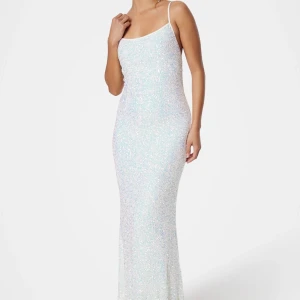 Glittrig långklänning med öppen rygg - Supersnygg långklänning i vitt med glittriga paljetter, smala axelband och öppen rygg med knyt. Använd endast en gång!