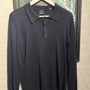 Långärmad piké merinoull - Snygg marinblå pikétröja från Only & Sons med klassisk krage och tre knappar framtill. Tröjan är långärmad och har en stilren, enkel design som passar perfekt till jeans eller chinos. Materialet är 100% merinoull och den är varm men fortfarande tunn och skön. Säljs då den blivit för liten på mig
