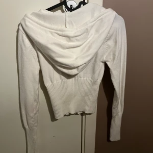 Kofta  - Finstickad kofta med ribbad midja och armar och stor luva 