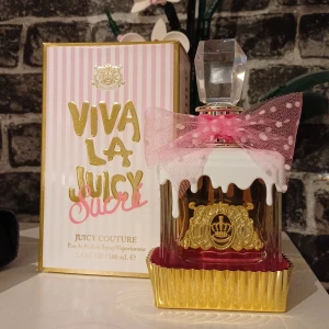 Viva La Juicy Sucré EdP 100ml - Färgglad och lekfull parfymflaska med cupcake-inspirerad design och rosa rosett. Volym: 100 mL.. Perfekt för dig som vill sticka ut med din doftsamling. Har testats, gissar ca 90-95% kvar. 🌷