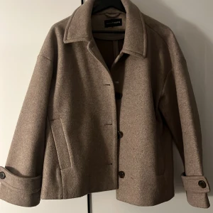 Beige kappa - Snygg beige rock från KappAhl med klassisk krage och stora knappar framtill. 