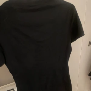 Svart t-shirt från Intimissimi - En klassisk svart t-shirt från Intimissimi i mjuk Supima-bomull. Modellen är enkel med rund halsringning och korta ärmar, perfekt för en clean och stilren look. Passar dig som gillar basic plagg med skön passform.