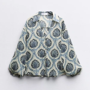 Blommig blå blus från Zara - Snygg blus från Zara med blommigt mönster, har långärmade puffärmar, klassisk krage och knappar framtill. 