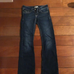 Mörkblå bootcut jeans med kontrastsömmar - Snygga mörkblå jeans med bootcut passform och tydliga kontrastsömmar. Klassisk femficksdesign med detaljerade bakfickor och sömmar. 