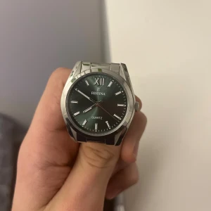 Silverfärgad Festina herrklocka ORG PRIS 1299kr - Stilren herrklocka från Festina med rund urtavla i grått och silverfärgade detaljer. Klockan har en robust länkarmband i rostfritt stål och tydliga indexmarkeringar samt romersk tolvmarkering. Quartz-urverk och snygg metallfinish.NYPRIS 999kr