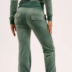 Juicy couture  - Mysiga gröna mjukisbyxor med raka ben och bred resår i midjan. Byxorna har stora fickor med lock och tryckknappar bak samt snörning framtill. Perfekta för chill dagar och en avslappnad look.