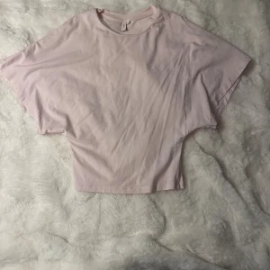 Ljusrosa topp från Nelly - Säljer en ljusrosa topp från Nelly i storlek S. Toppen har en loose passform öpptill och tajt i midjan med breda korta ärmar och rund halsringning. Materialet är mjuk bomull som känns skönt mot huden. Perfekt för dig som gillar enkel och chill stil.