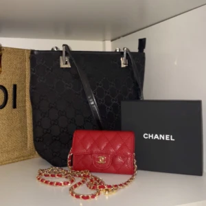 Röd  kuvertväska i skinn - Supersnygg röd kuvertväska i quiltat skinn med guldfärgad kedja och klassisk. Kommer med originalbox, dustbag och äkthetskort. Perfekt storlek för det viktigaste och ger en lyxig touch till din outfit.