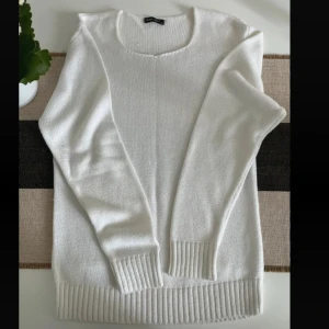 Vit stickad tröja Polim Pier L/XL - Snygg vit stickad tröja från Polim Pier i storlek L/XL. Tröjan har rund hals, långa ärmar och breda ribbade muddar vid ärmslut och nederkant. Perfekt för dig som gillar enkel och clean stil med mjukt material. Helt ny.