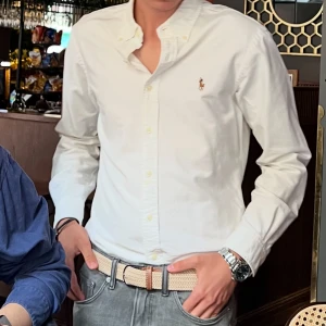Äkta Vit slim fit skjorta Polo Ralph Lauren - Vit skjorta från Polo Ralph Lauren i slim fit med klassisk krage och broderad logga på bröstet. Långärmad modell med knappar hela vägen och tillverkad i mjuk bomull. Perfekt för dig som gillar stilrena och tidlösa plagg.
