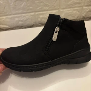 Svarta boots med dragkedja storlek 36, tjej/dam - Svarta boots från Clou Comfort i storlek 36. Skorna har en rund tå, grov sula och dragkedja på sidan för enkel påtagning. Tillverkade i syntetmaterial med en stilren och enkel design som passar till många outfits. Min barn har använt den en gång men det passade inte för henne. Perfekt för vintern.