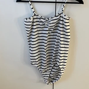 Randig bikini från Vero Moda - Snygg bikini från Vero Moda i storlek Large med marinblå och vita ränder. Modellen har smala axelband och klassisk form, perfekt för strandhäng. Materialet är mjukt och bekvämt, troligtvis bomull eller syntet. Enkelt och stilrent mönster som passar dig som gillar en fräsch look.