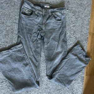 Grå jeans från Gina Tricot, storlek 170 - Snygga grå jeans från Gina Tricot bootcut. Klassisk femficksdesign med silverfärgade knappar och bälteshällor. Jeansen har en neutral grå nyans och är tillverkade i mjukt bomullsmaterial med en skön passform. Lite stor i storlek! Går såklart att stryka (blir mycket finare då) har dock ingen strykjärn den gick sönder precis.. 