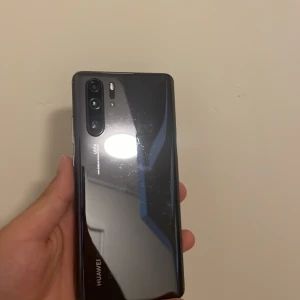 Huawei P30 Pro - Huawei P30 Pro med Leica-kamera. Baksidan har repor och framskärmen är sprucken i hörnet. Telefonen har USB-C-port och flera kameralinser. Perfekt för dig som söker en prisvärd mobil med avancerad kamera, men kan acceptera kosmetiska defekter.