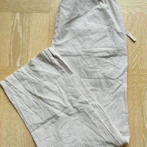  Pyjamasbyxor S - Beige och vitrandiga pyjamasbyxor i bomulll från Lager 157, stl S med resår och knytning i midjan. Har bara använts någon enstaka gång så i nyskick. Innerbenslängd 74cm