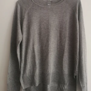 Grå stickad tröja från Zara - En enkel och stilren grå finstickad tröja från Zara i storlek S. Tröjan har rund hals, långa ärmar och ribbade muddar vid ärmslut och nederkant. Materialet ( akryl och viscose) är mjukt och känns skönt mot huden. 