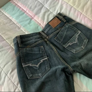 Diesel jeans high waist straight fit blå - Snygga blå jeans från Diesel med klassisk femficksdesign och coola detaljer på bakfickorna. Jeansen har raka ben och tydliga kontrastsömmar. Märkespatch i läder baktill och Diesel-logga på myntfickan. Perfekta för dig som gillar en tidlös look. Helt nya då dem endast varit provade! Ge bud!